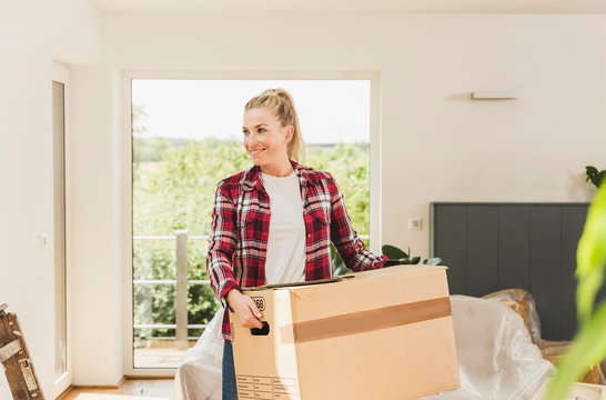 Woman moving into new home carrying cardboard box