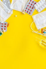Treat flu and cold concept. Vaccine, mask, pills on yellow background top view frame copy space