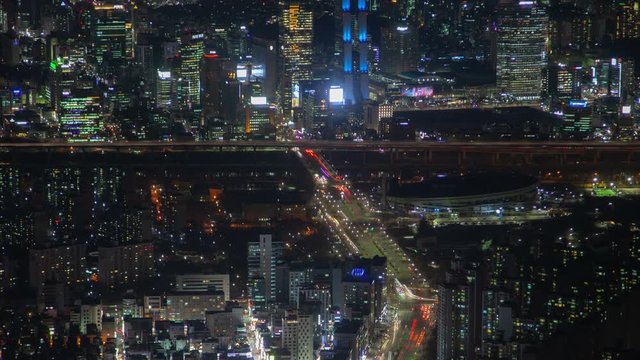 SEOUL/KOREA - MAY 29 2019: Timelapse Seoul illuminated highrise buildings with flashing advertising displays surround overpass highway with river bridge lights at night zoom in on May 29 in Seoul