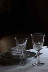 Served cutlery sets, plates, napkins, empty crystal wine glasses, on tables in a restaurant.