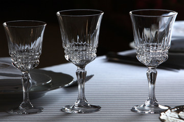 Served cutlery sets, plates, napkins, empty crystal wine glasses, on tables in a restaurant.