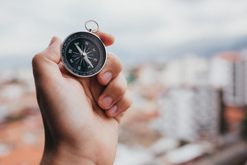 One hand holding a metal compass