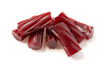 Several pieces of thick red licorice on a white background.