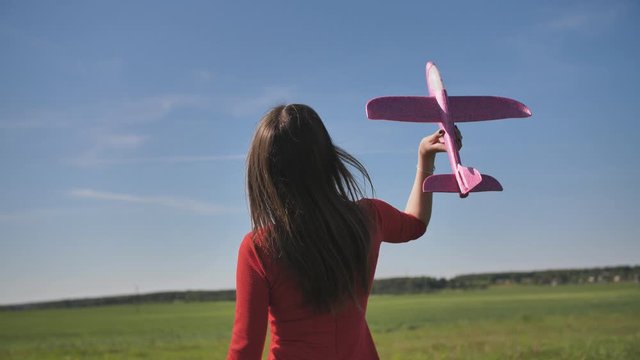 A girl launches a toy paralon airplane into the sky.