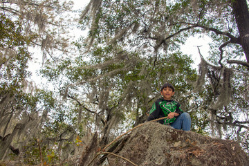 niño latino en la naturaleza entre rocas y cuerdas en el otoño