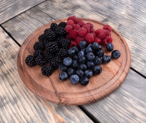 A group of colorful blackberries, blueberries and raspberries in a textured wooden background