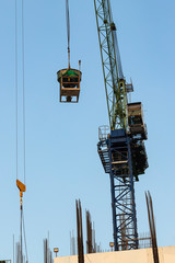 Construction cranes and construction workers on building site.