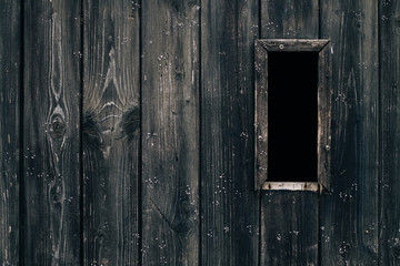 Spooky dark black vertical window in rustic brown ancient textured wood door / Halloween horror...