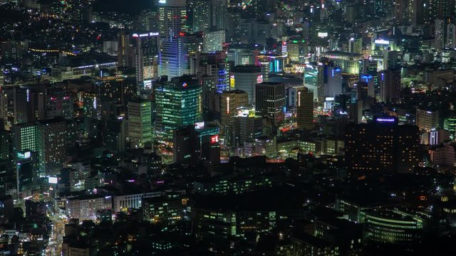 Timelapse flashing advertisement illumination of different colours on modern Seoul highrise buildings and skyscrapers near street highways at deep night zoom in