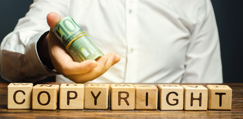 Wooden blocks with the word Copyright and euro bills in the hands of a businessman. Purchasing...