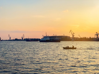 Fototapeta premium River port with ships at sunset. Busy traffic artery. Logistics and infrastructure. Loading and unloading of ships, trade traffic. Industry and economics. Plants and factories. Transport hub. Dnipro