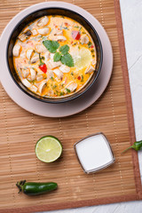 famous delicious Thai Tom yum spicy soup with champignon on bamboo napkin. served on white table. flat lay
