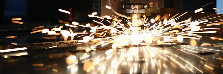 Sparks fly out machine head for metal processing laser metal on metallurgical plant background....