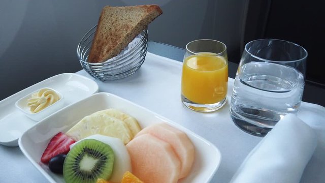 Delicious breakfast with fruit served on board of business class airplane. Tray of food in the airplane. Tray of food on the plane, business class travel. 