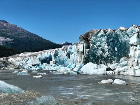 Taku Glacier in Alaska. Close to Juneau, view from airboat. Glacier is melting into the grey river. Blue pieces of ice.
