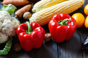 Thanksgiving holiday vegetables on brown table. Autumn corn, pepper, pumpkins. Healthy food, Vegetarianism. Fresh vegetables on wooden background, top view.