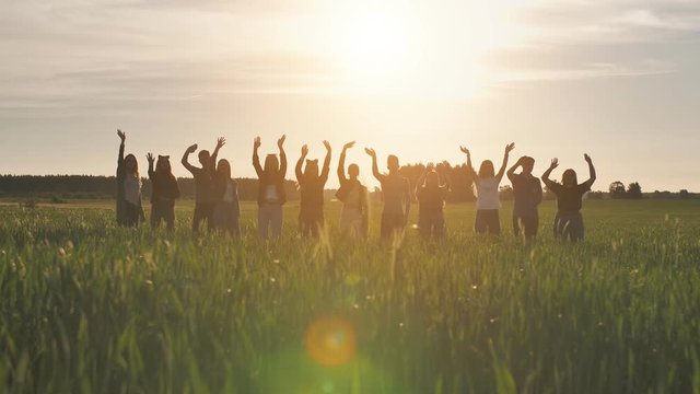 The concept of parting or goodbye. Silhouettes of young people waving hands at sunset.