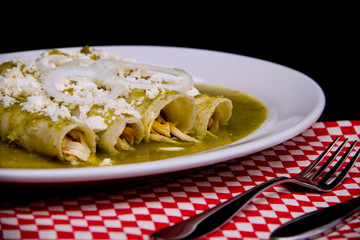 Authentic Mexican enchiladas smothered in green sauce, topped with melted cheese and creamy sour cream—vibrant dish for culinary visuals and food branding.