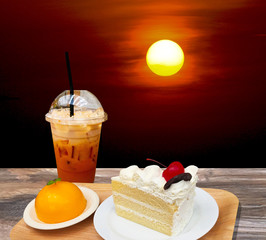 Rising sun with layer cake with berry on top and orange cake on wooden plate with cup of cold milk...