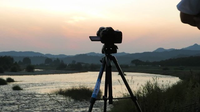 男性カメラマン　夕日　撮影　デジタル一眼レフカメラ