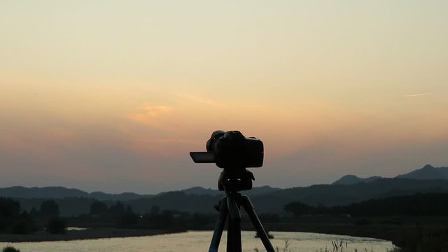 男性カメラマン　夕日　撮影　デジタル一眼レフカメラ