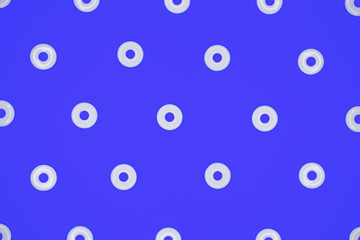 Flat round white plastic beads in regular pattern on blue cardboard background