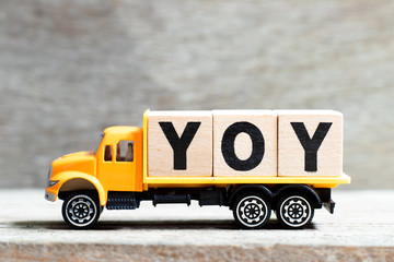 Truck hold letter block in word YOY (abbreviation of year over year) on wood background