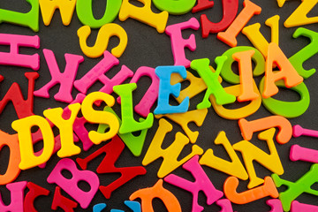 Reading and writing struggle, difficulty spelling and learning impairment conceptual idea with random colorful letters and the word dyslexia spelled in a hard to read manner