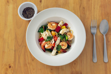 food background of spices green pepper spaghetti with variety of seafood shirmp, fish and squids on wooden table