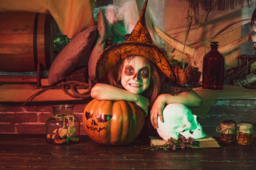 Halloween party with child wearing Halloween costumes. Funny witch with a pumpkin. Halloween decorations. Home Halloween atmosphere.