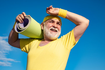 Old man with fitness yoga carpets - close up portrait. Sport and retirement concept. Healthcare...