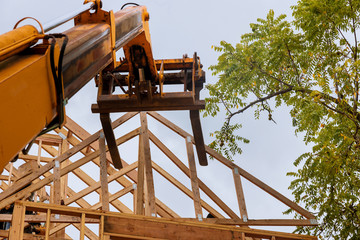 A wooden roof truss being lifted by a boom truck forklift in the roof a new home © ungvar
