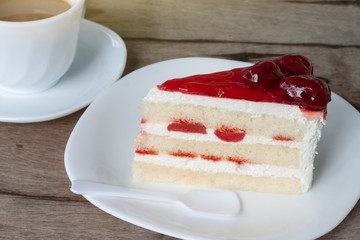 Strawberry cheesecake with a cup of coffee on wooden table in the morning.