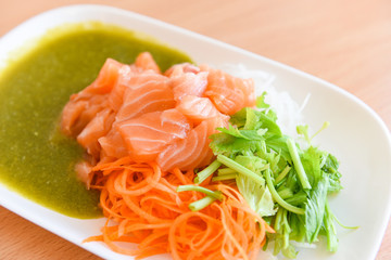 Japanese food raw sashimi salmon fillet with carrot celery seafood sauce in the restaurant / salmon salad menu set Japanese cuisine fresh ingredients on plate