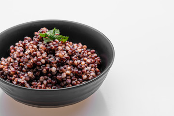 Cooked Sorghum (also known as sorgo) in a back bowl, isolated