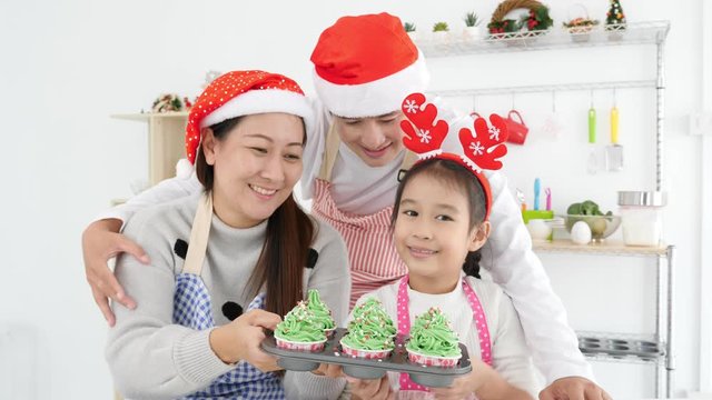 Asian family pround to present their homemade christmas cup cakes at camera,smiling happily together.