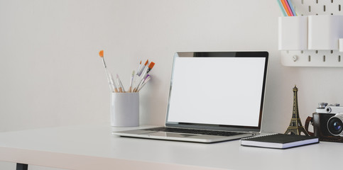 Minimal artist workspace with blank screen laptop computer with camera and decorations