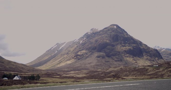 4K A Road through The Glen Coe Scottish Mountains. Cars travelling within a remote rural Tourist destination in Scotland.