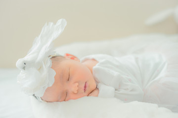 adorable infant girl in white pajama sleeping on white cloth mattress. newborn baby having day nap in parents' bed. childhood dreams. concept of health and children.