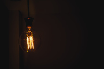 Glowing light bulb in the dark on wall and copy space for text, idea concept