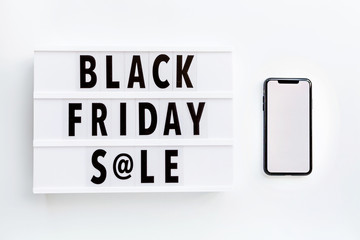 Creative promotion composition Black friday sale text on lightbox and mobile phone on white background. Flat lay, top view, overhead, mockup, copy space, template