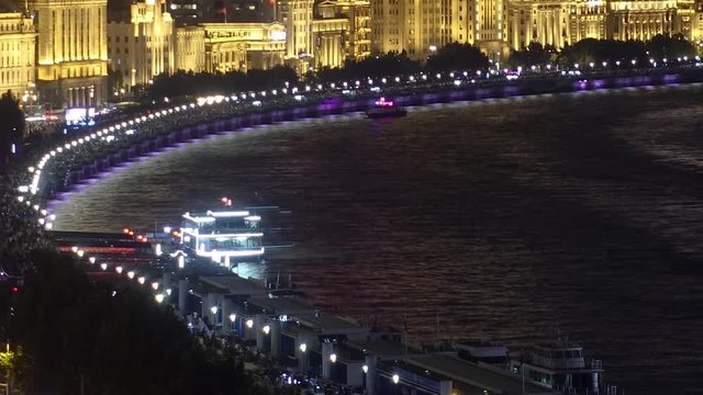 Moving night time lapse of boats at Shanghai bund. Evening at old Shanghai river front timelapse. Tourist cruise ships sail and dock at Huangpu riverbank. Old British architecture in heritage area.