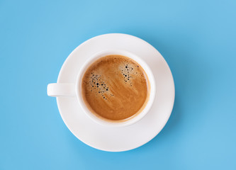 Top view of hot coffee and foam in white cup isolated on blue background and copy space.Coffee menu in the coffee shop or restaurant.