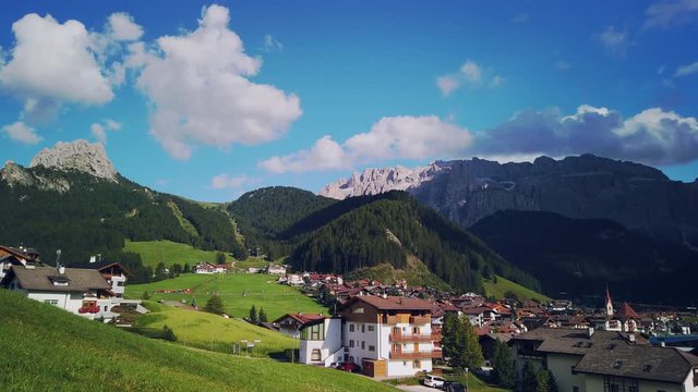 Pan across Selva Val Gardena (Wolkenstein im Gr&ouml;den) with clouds forming over the peaks of the Dolomites.
