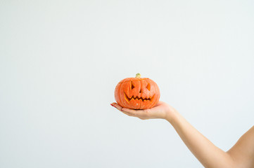 Female hand holding a pumpkin for Halloween. Close-up jack-o'-lantern cover on a white background on the eve of all the saints. front view. Hand made for the holiday. Trick or treat.