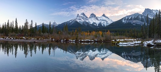Three Sisters Snowy Mountain Peaks Reflection in Calm Water Wide Panoramic Landscape near Canmore, Alberta Foothills of Canadian Rocky Mountains - obrazy, fototapety, plakaty