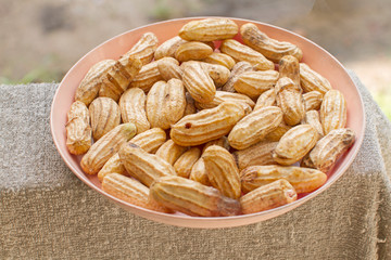 Closeup of dried peanuts in bowl isolated on white background.
