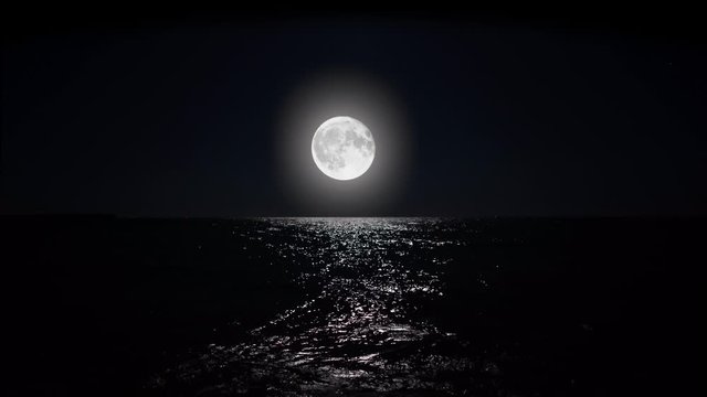 Big full moon at night reflecting on the water. Alpha channel moonlight bright sea reflection. Clear big distinct moon glowing over the ocean in eerie night scene.