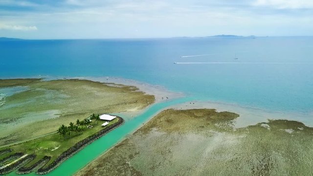 Aerial view of artificial island with wedding preparations, canoos and speedboat in background