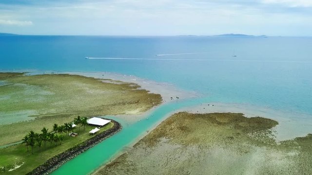 Aerial view of artificial island with wedding preparations, canoos and speedboat in background